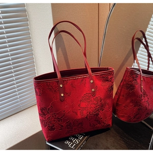 Close-up of red floral jacquard tote bag with elegant golden rivet details and texture