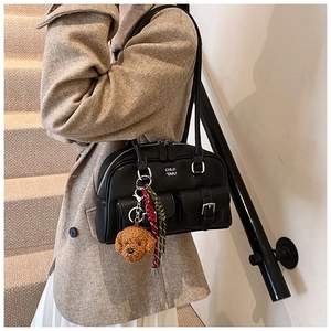 Detail of black vintage bowling bag with fluffy teddy charm and white logo print
