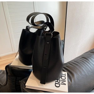 Close-up of black litchi grain leather texture on a minimalist bucket shoulder bag