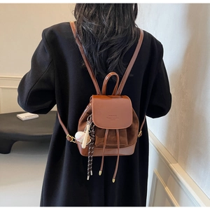 Close-up of caramel brown mini backpack with drawstring and stylish baseball charm detail