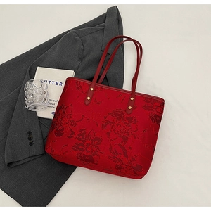 Close-up of red tote bag featuring vintage floral texture and long dual handles