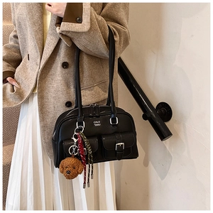 Close-up of black leather bowling bag featuring decorative teddy bear charm and side pockets