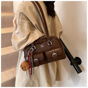 Close-up of dark brown vintage bowling bag featuring metal buckle pockets and plush bear charm