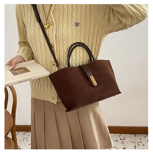 Detail of a dark brown suede tote bag featuring leather straps and golden metal buckle