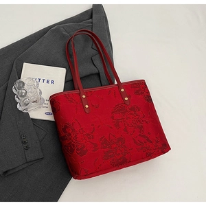 Macro detail of red floral jacquard tote bag with leather handles and gold rivets
