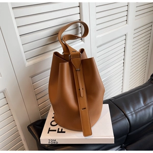 Close-up of brown litchi pattern leather bucket bag with wide adjustable shoulder strap