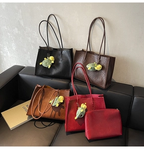 Close-up of four large faux leather tote bags in various colors on a black sofa