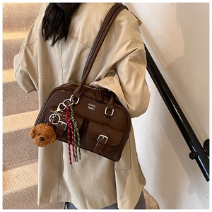Close-up of vintage brown leather bowling bag featuring decorative teddy bear pendant