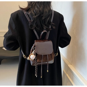 Detail of dark brown mini backpack with drawstring closure and baseball glove pendant