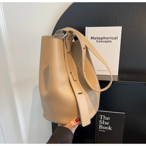Detailed close-up of khaki bucket bag showing the premium pebble leather and wide strap