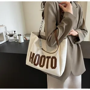 Détail du grand sac cabas blanc cassé avec patch en cuir HOOTO et bandoulière en chaîne