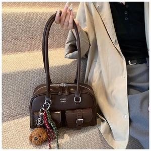 Detail of dark brown leather bowling bag with plush dog charm and side pockets