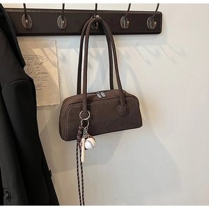Detail of dark brown suede shoulder bag with debossed logo and baseball themed charm