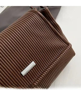 Détail de la texture plissée marron et de la boucle en métal argenté du sac à bandoulière