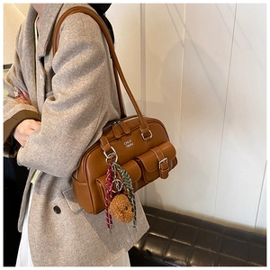 Close-up of caramel brown shoulder bag with functional pockets and plush bear charm
