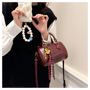 Close-up of wine red Boston bag with pleated texture, gold key and heart lock charms