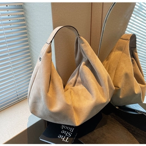 Close-up of beige suede hobo bag with a minimalist half-moon silhouette and zipper