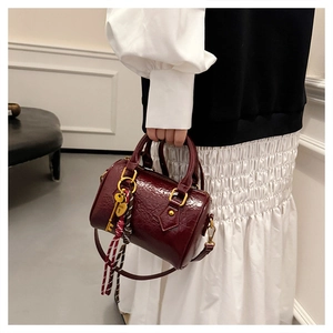 Detail of burgundy embossed Boston bag with golden hardware and heart lock pendant