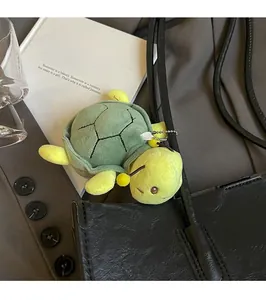 Detailed view of a green plush turtle charm attached to a luxury black leather tote bag