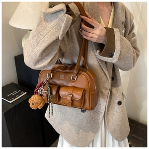 Close-up of vintage brown leather bowling bag featuring flap pockets and plush dog charm