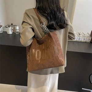 Détail du sac cabas en cuir marron avec bandoulière en chaîne et logo en relief