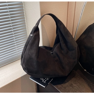 Detailed view of large black suede tote bag in an elegant minimalist interior setting