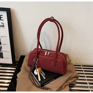 Detail of red suede Boston shoulder bag featuring logo embossing and baseball keychain