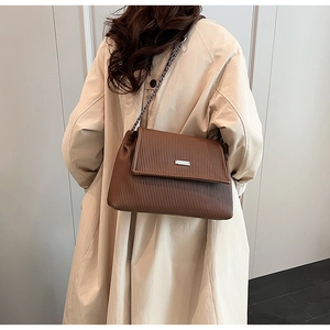 Détail de la texture en cuir plissé marron foncé et boucle argentée du sac à main