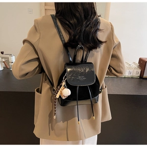 Detail of black mini backpack with contrast textures and stylish baseball charms on side