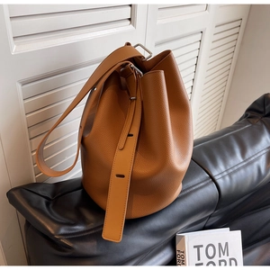 Close-up of litchi texture leather bucket bag with wide shoulder strap and metal buckle