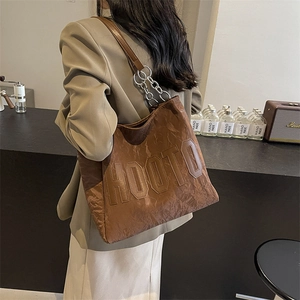 Détail d'un sac cabas marron en tissu texturé avec des maillons de chaîne argentés