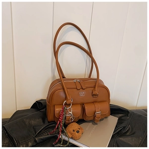 Detail view of caramel brown retro handbag with plush bear charm and pocket textures