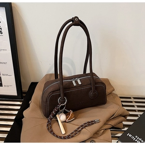 Detail showing the dark brown leather handbag with MUYETI logo and sports theme keychain