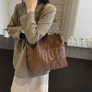 Sac cabas marron avec lettrage HOOTO et bandoulière chaîne, porté sur un blazer kaki