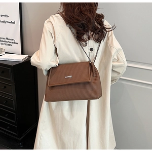 Sac fourre-tout plissé marron avec chaîne argentée porté par un mannequin en studio