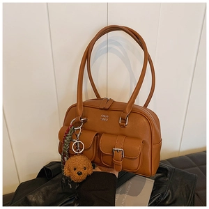 Detailed view of the caramel leather bowling bag with vintage pockets and bear charm