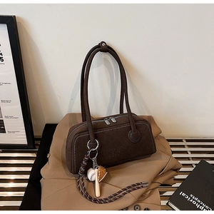 Detail of dark brown suede shoulder bag featuring contrast white stitching and metal zippers