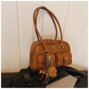 Detail view of vintage caramel brown bowling bag with plush bear and woven charms