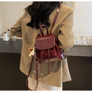 Detail of burgundy leather backpack featuring premium suede panels and drawstring closure
