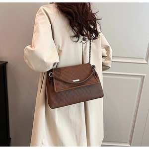 Détail d'un sac cabas plissé marron foncé avec boucle argentée sur un trench-coat