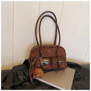 Detail of dark brown bowling bag with silver buckles and plush dog charm on leather