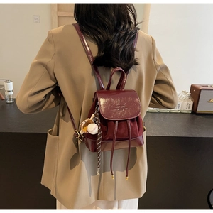 Detail of burgundy leather mini backpack with suede panels and sports glove charm