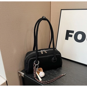 Detail view of black canvas shoulder bag with white contrast stitching and baseball charms