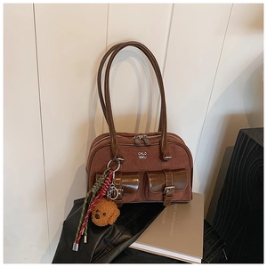 Detail of brown suede handbag featuring front pockets and a cute teddy bear charm