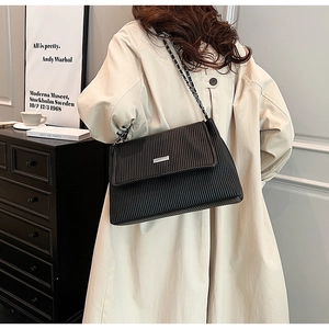 Détail du sac cabas plissé noir avec bandoulière chaîne argentée et boucle métallique