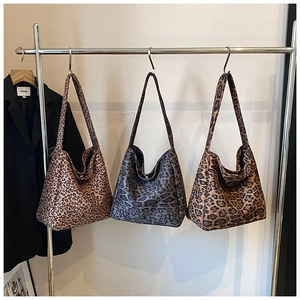Three leopard print hobo tote bags in brown, grey and tan hanging on a metal rack