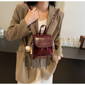 Detail of burgundy mini backpack with adjustable straps and baseball charm accessory