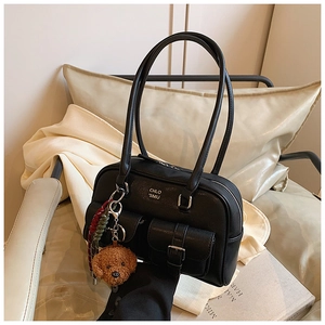 Detail of vintage black bowling bag with decorative buckle pockets and a cute bear charm