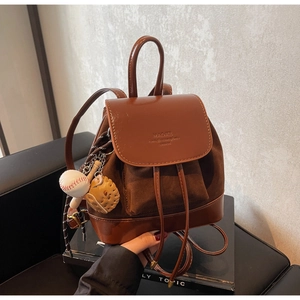 Close-up of vintage brown backpack featuring drawstring closure and baseball charms
