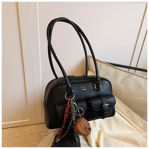 Close-up of black retro bowling bag featuring twin front pockets and plush bear charm